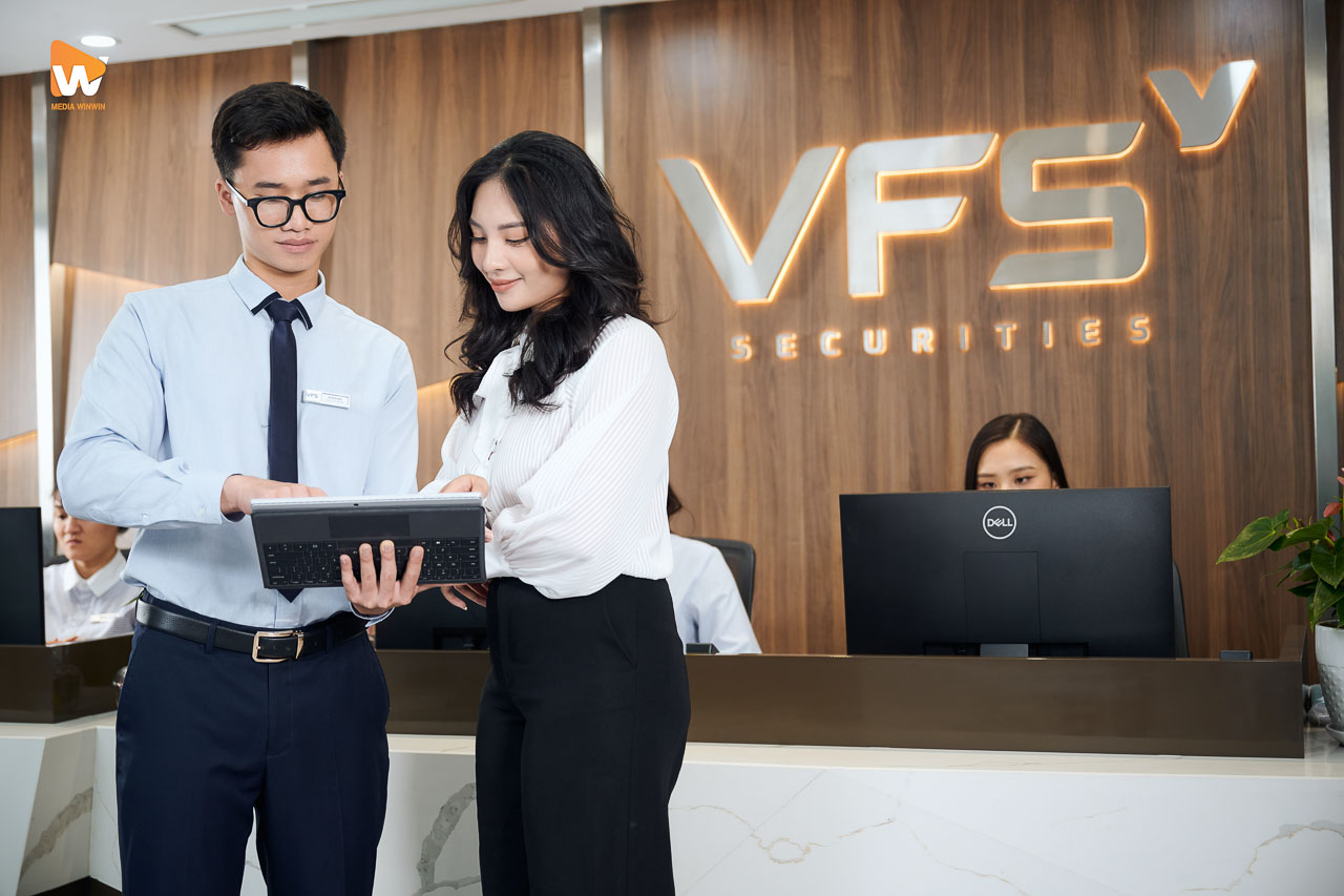 2 nhân sự VFS Securities trao đổi trước logo thương hiệu tại quầy giao dịch